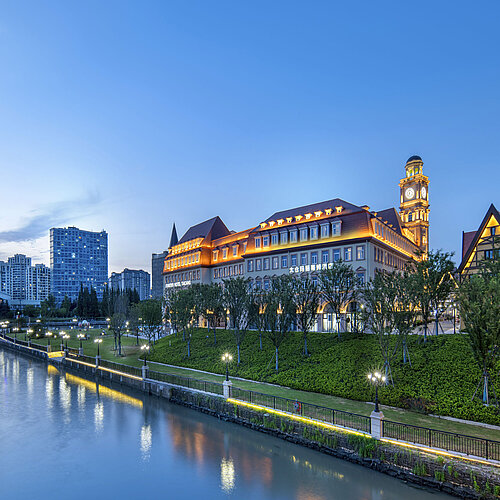 Maritim Hotel Taicang am Fluss bei Abenddämmerung mit beleuchtetem Gebäude und moderner Skyline im Hintergrund